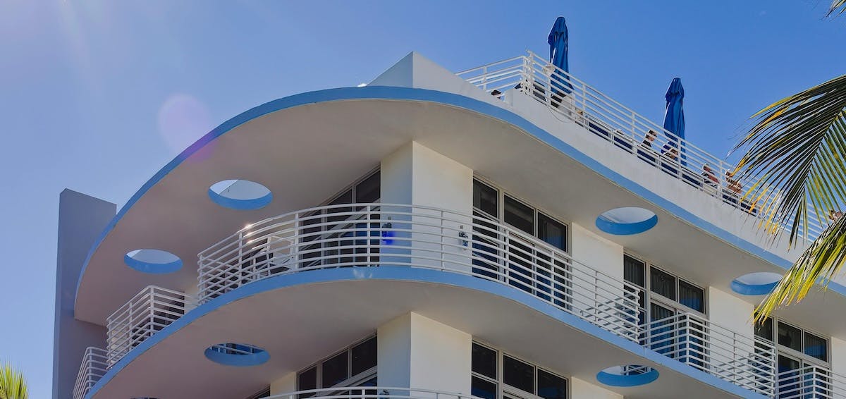 A photo of Miami condos, showing white balconies with blue trim and a blue sky and palm trees in the background