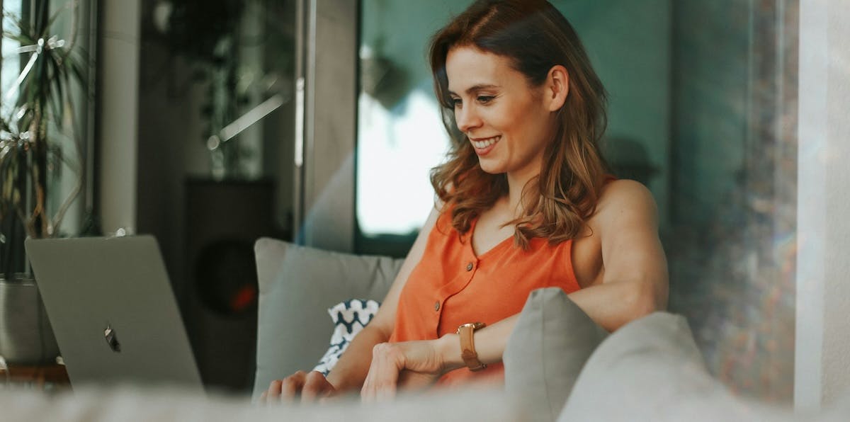 A woman uses her laptop on her couch to manage her rental home