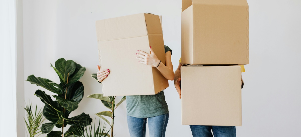 A renting couple hold moving boxes