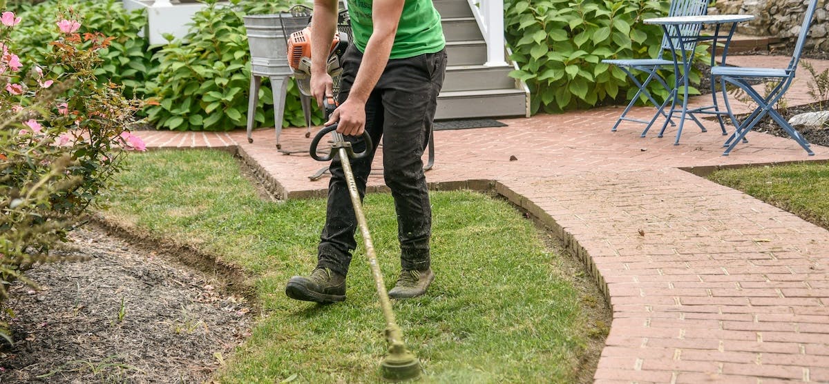 A man trims the lawn on his rental home