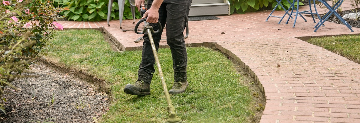 A man trims the lawn of a rental home in Summer