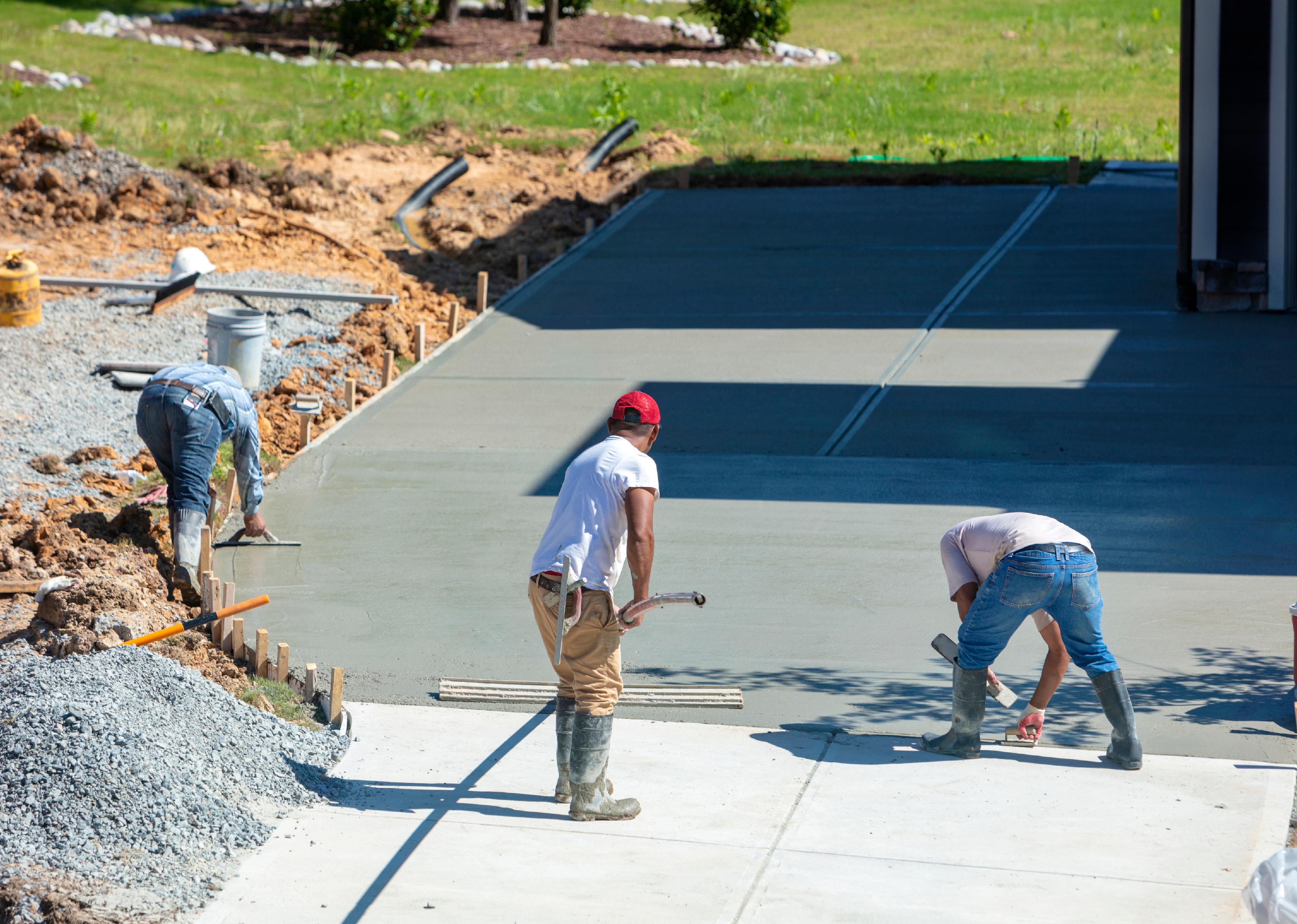 Three contractors smoothing a concrete foundation