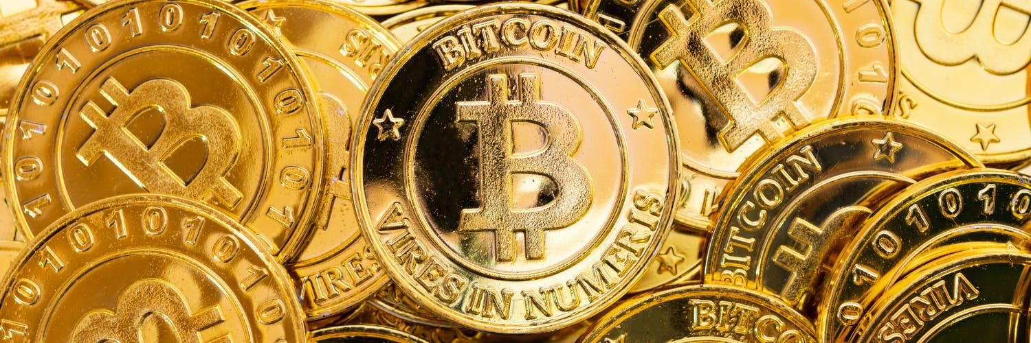 An image representing physical bitcoins, with the bitcoin logo printed on gold coins 