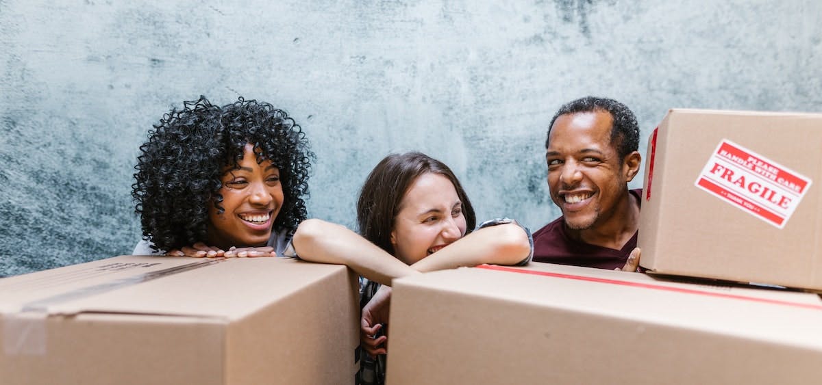 A photo of three adults with moving boxes, preparing to move into a sharehouse arrangement where you rent your home to multiple residents rather than a single lease agreement