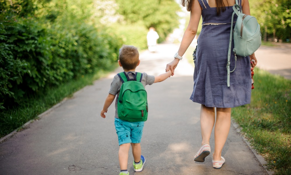 Mother walks her young son to school, carrying backpack. Walking in a desirable rental neighborhood with a great school district. 