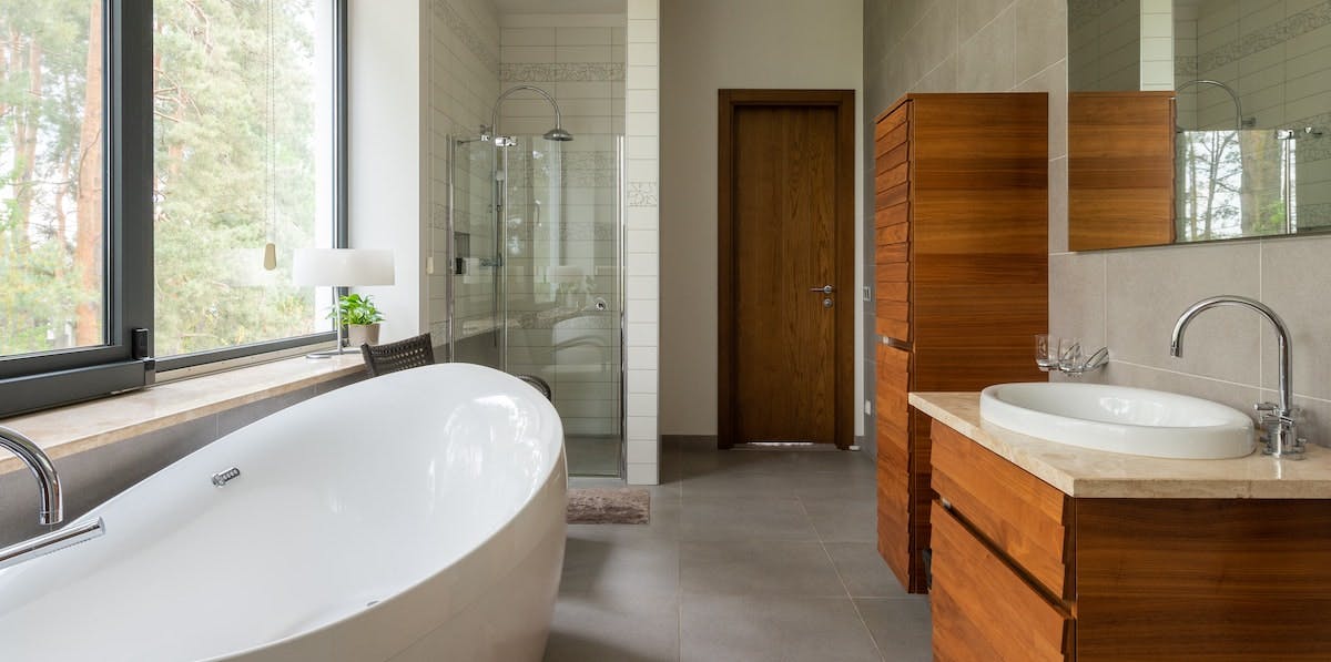 An image of a modern, remodeled bathroom with bathtub, shower and vanity. Find out the average cost of a bathroom remodel in this article. 