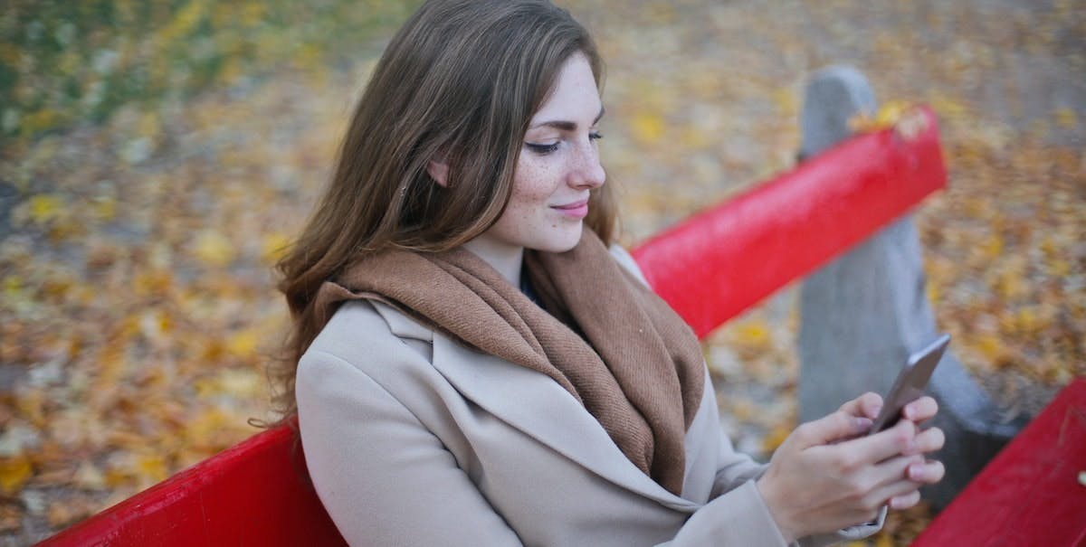 A young woman uses a smartphone to manage her rental property from the Belong app