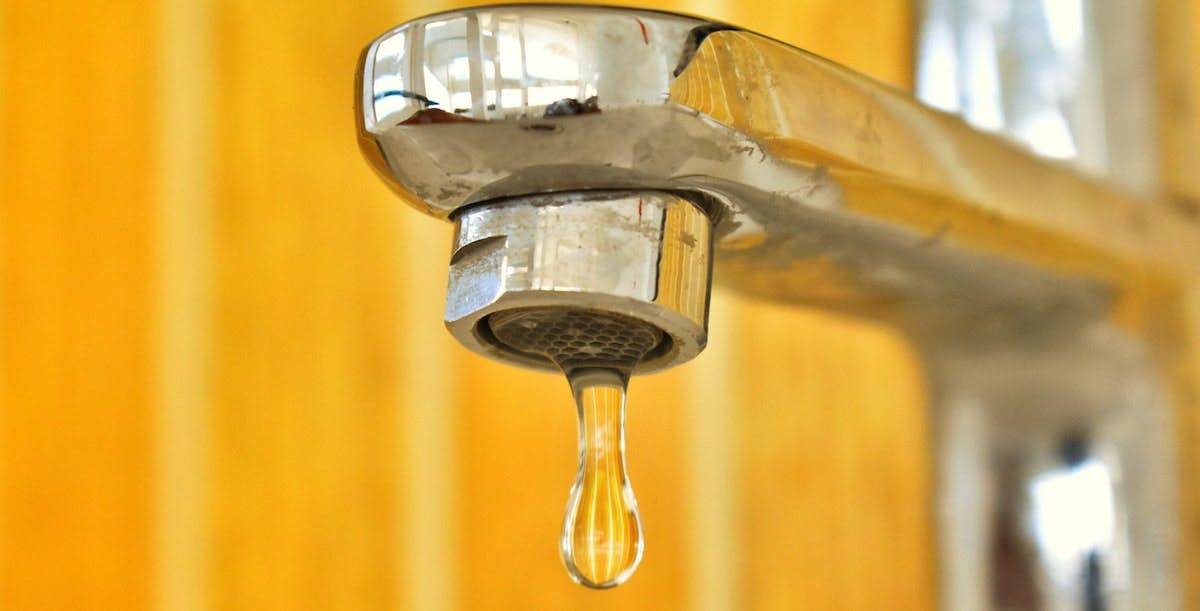 A close-up of a leaky faucet - a common rental property repair that landlords need to budget for