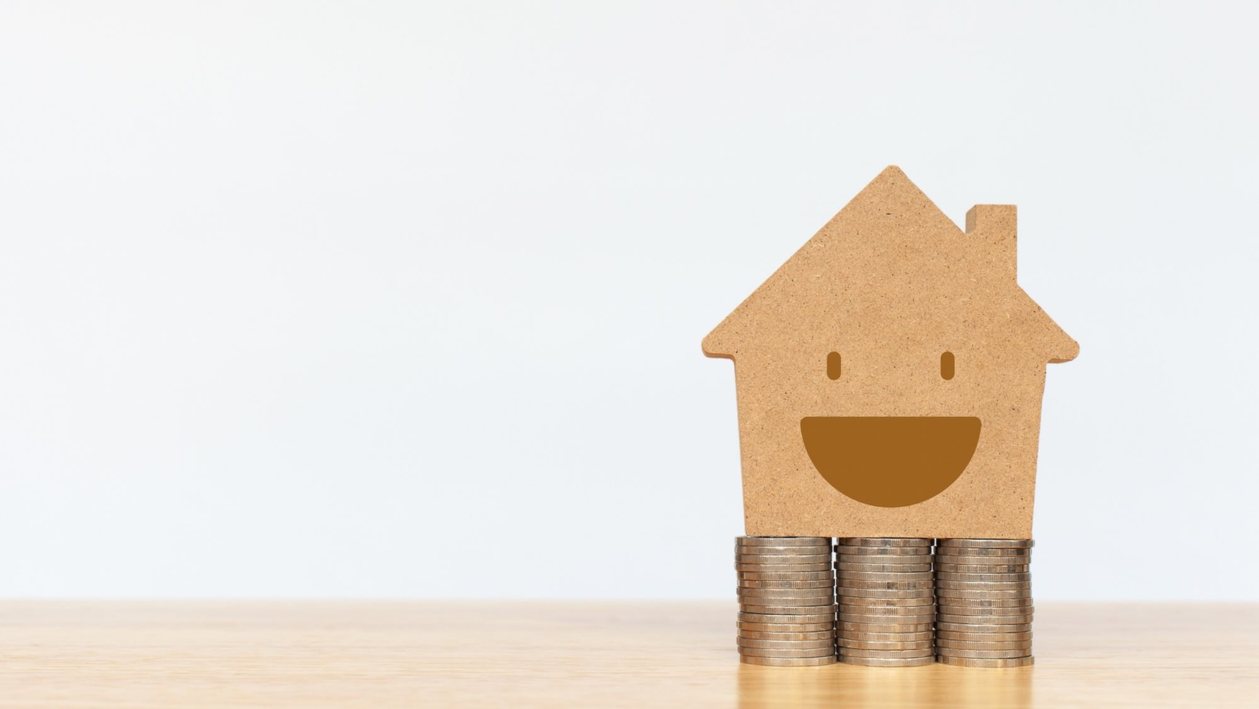 Happy smiling home sitting on top of coins, depicting a happy and profitable rental home