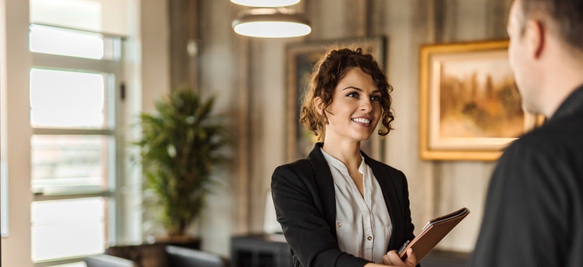 A young woman holding a notepad and shaking hands with a male, preparing for an interview with a property manager