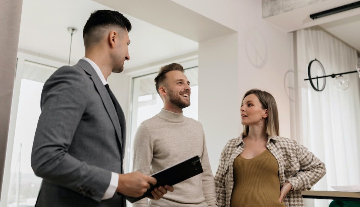 A young couple speaks to a property manager while looking at a rental home. Great tenants and the right approach can reduce vacancies in rental properties.