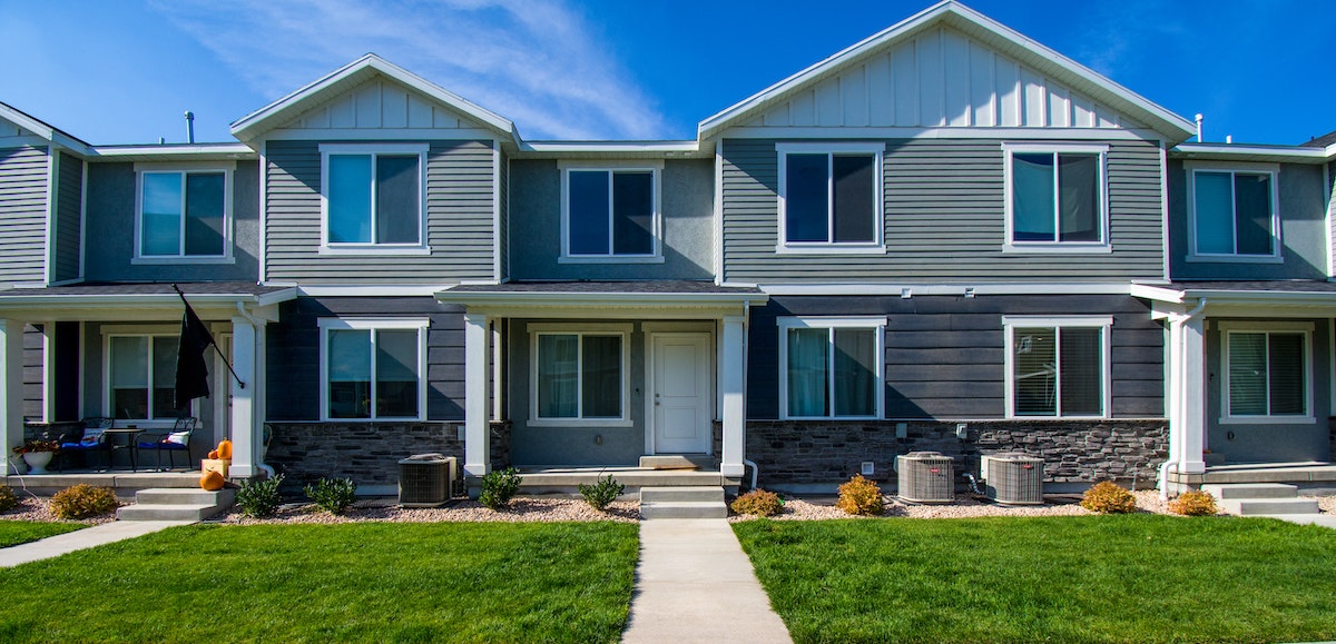 A real estate photo of grey and white homes in the US, accompanying an article about rent control for landlords