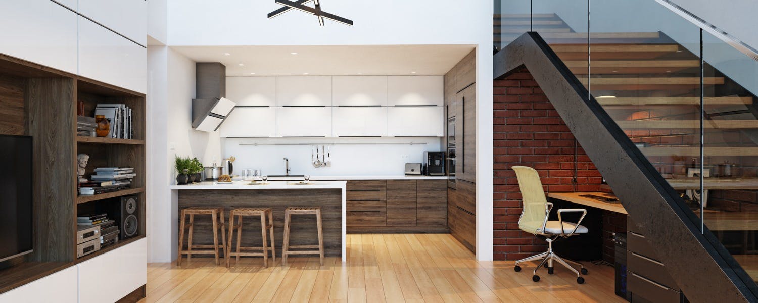 A desk located under a staircase by a kitchen for a space-saving home office solution