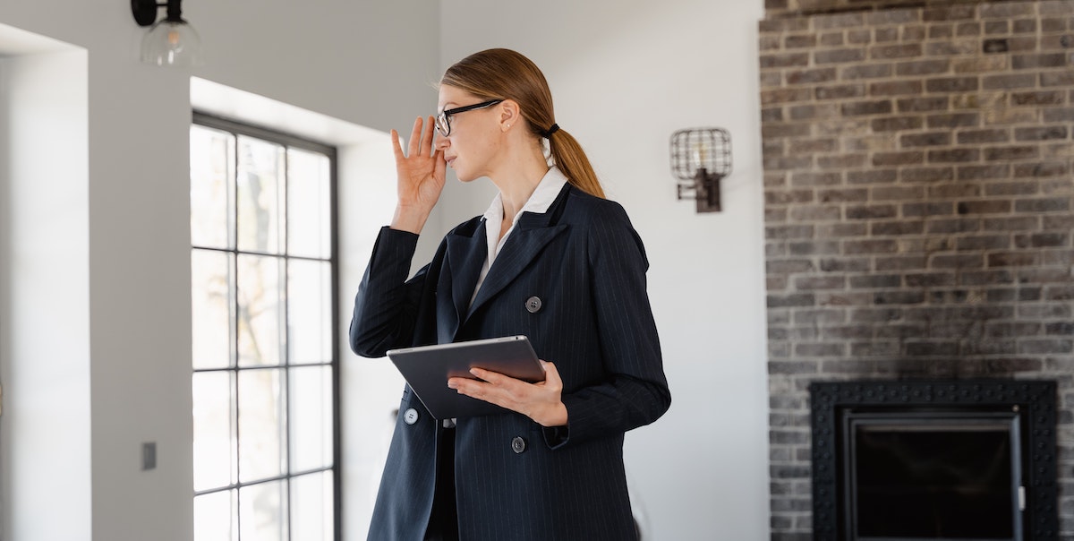 An image of a female property manager holding an iPad while inspecting a property. Find out what regulations property managers need to abide by - including property management companies and self-managing landlords