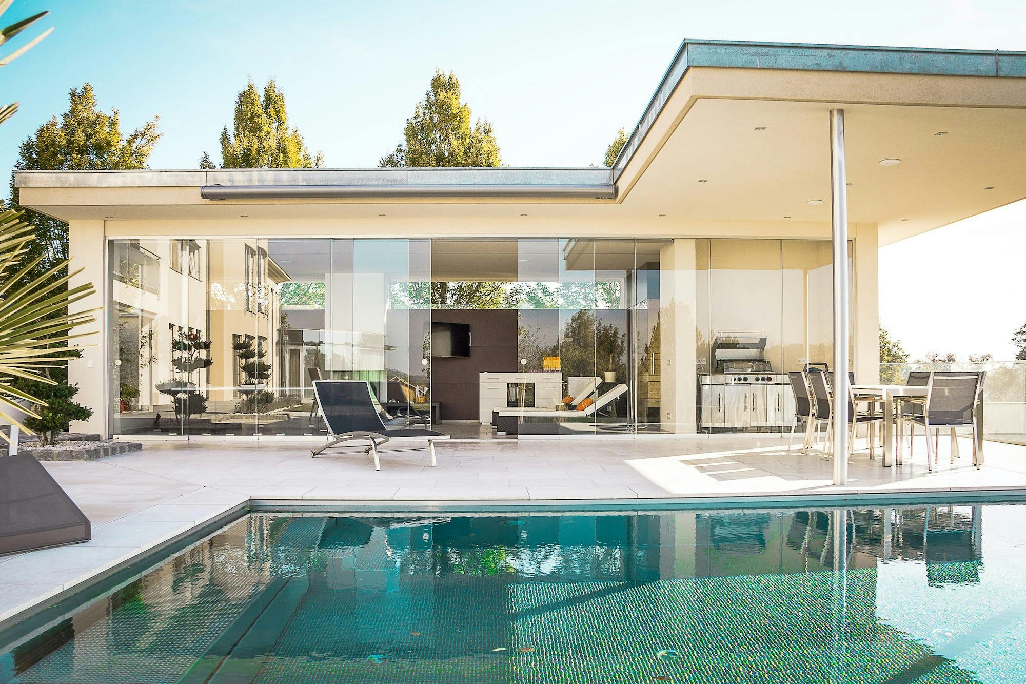 The backyard and side-view of a modern home with a swimming pool, pictured on a sunny day 