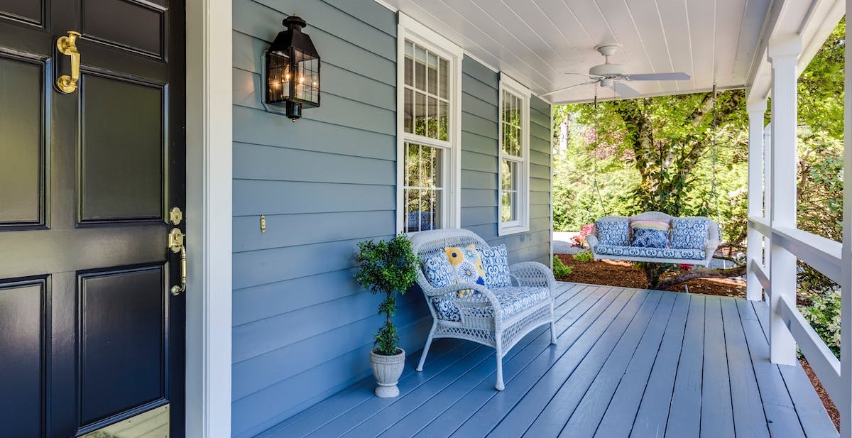 A photo of a front porch with swing and chair, painted blue. Keep your home and your rental home safe with both homeowners and landlords insurance.