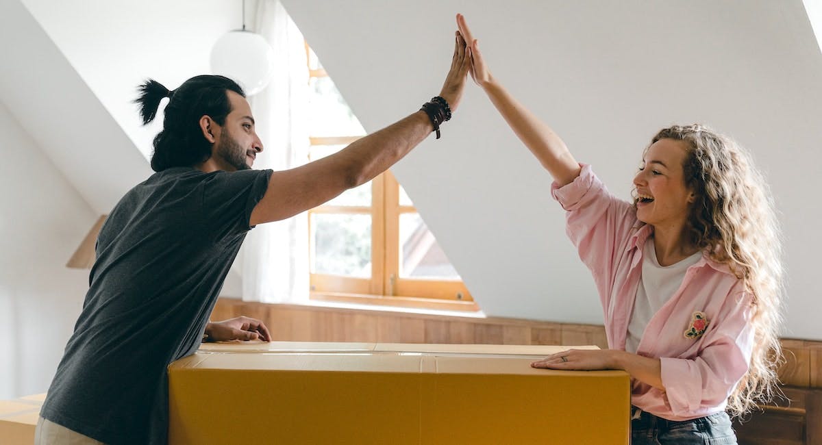 A couple high-five while unpacking, moving into a long-term rental property 