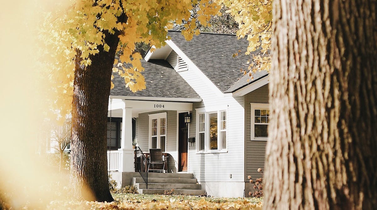 A single family home in Washington state, viewed through trees in the fall with yellow leaves