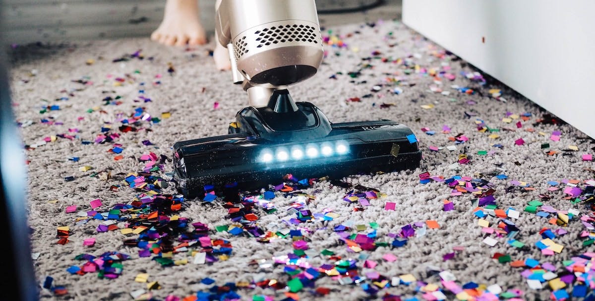 An image of a vacuum cleaner trying to remove glitter and confetti from a rug. Parties and hefty cleaning requirements are part of hosting on Airbnb, is it time to switch your home to a long-term rental? 