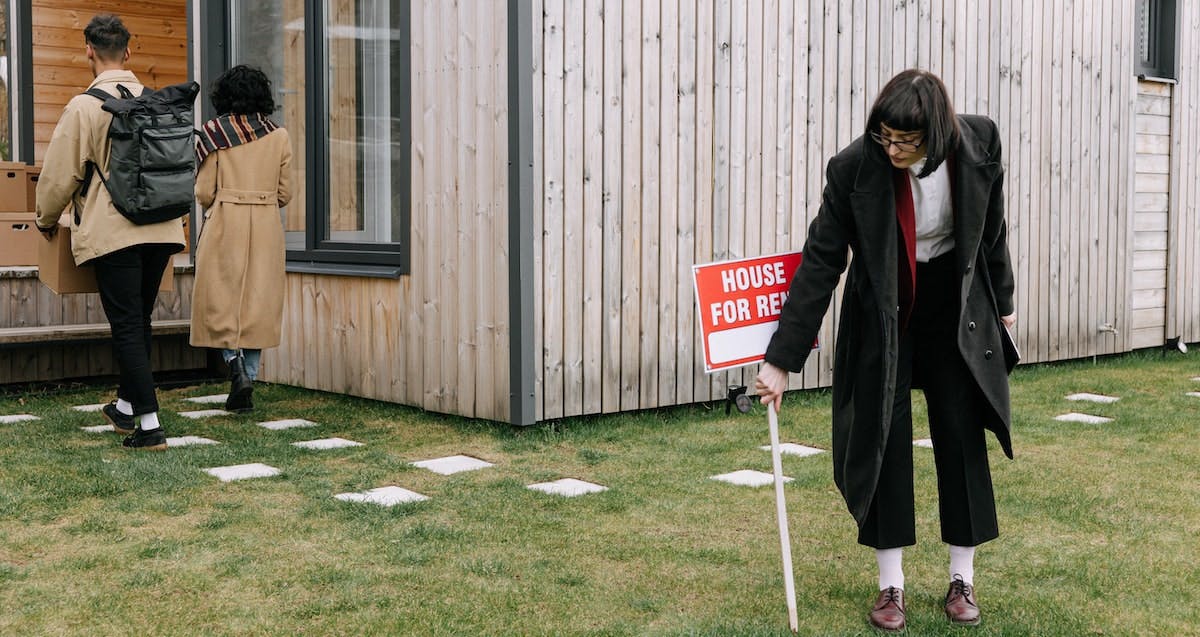 A property manager places a 'house for rent' sign in the yard of a single-family rental property. Find out if you really need a property manager for your rental home.