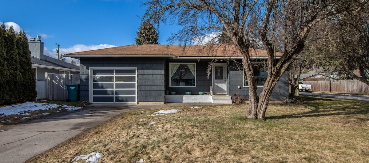 A single-family home on a sunny day, with snowfall melting in the front lawn. If you own a rental home in Washington state, read this annual maintenance checklist to plan how to keep your property in good repair all year round. 