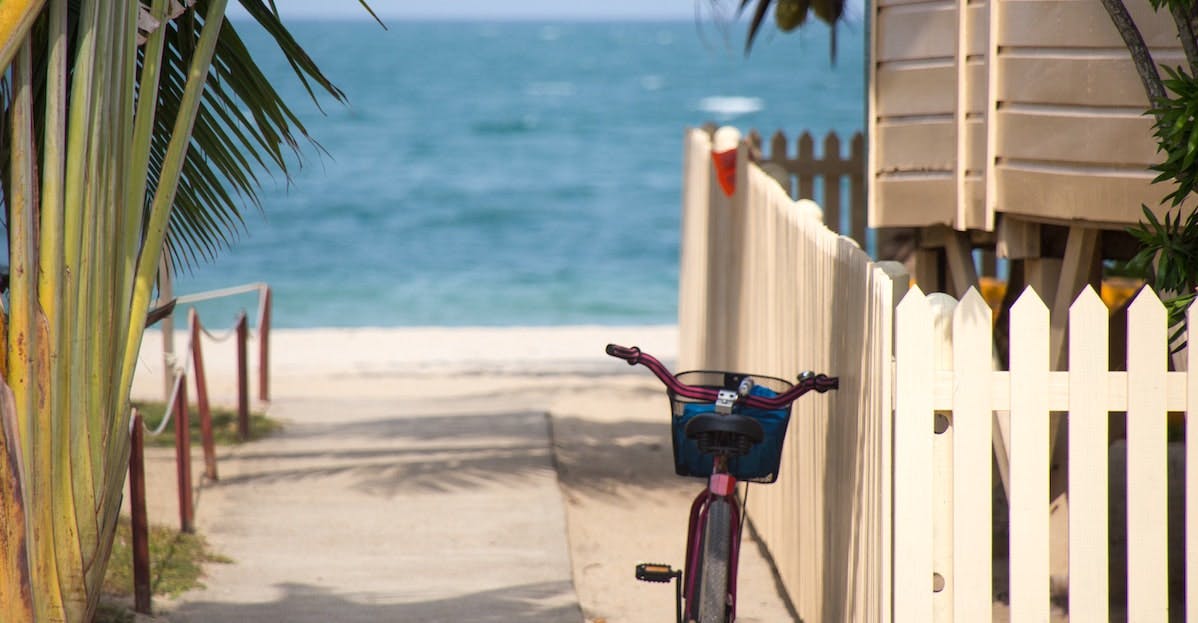 A bike is propped against a white picket fence in Key West, Florida. Summer in Florida is the best time to put your home on the rental market