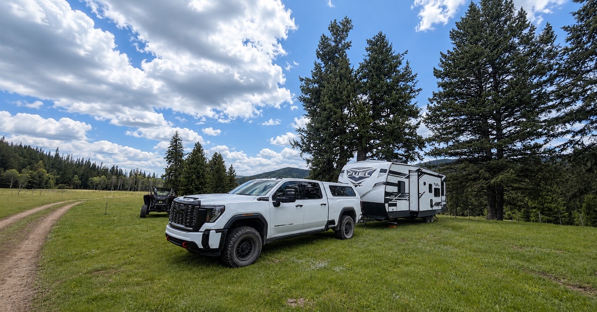 PPF-wrapped GMC truck and travel trailer parked in a mountain meadow