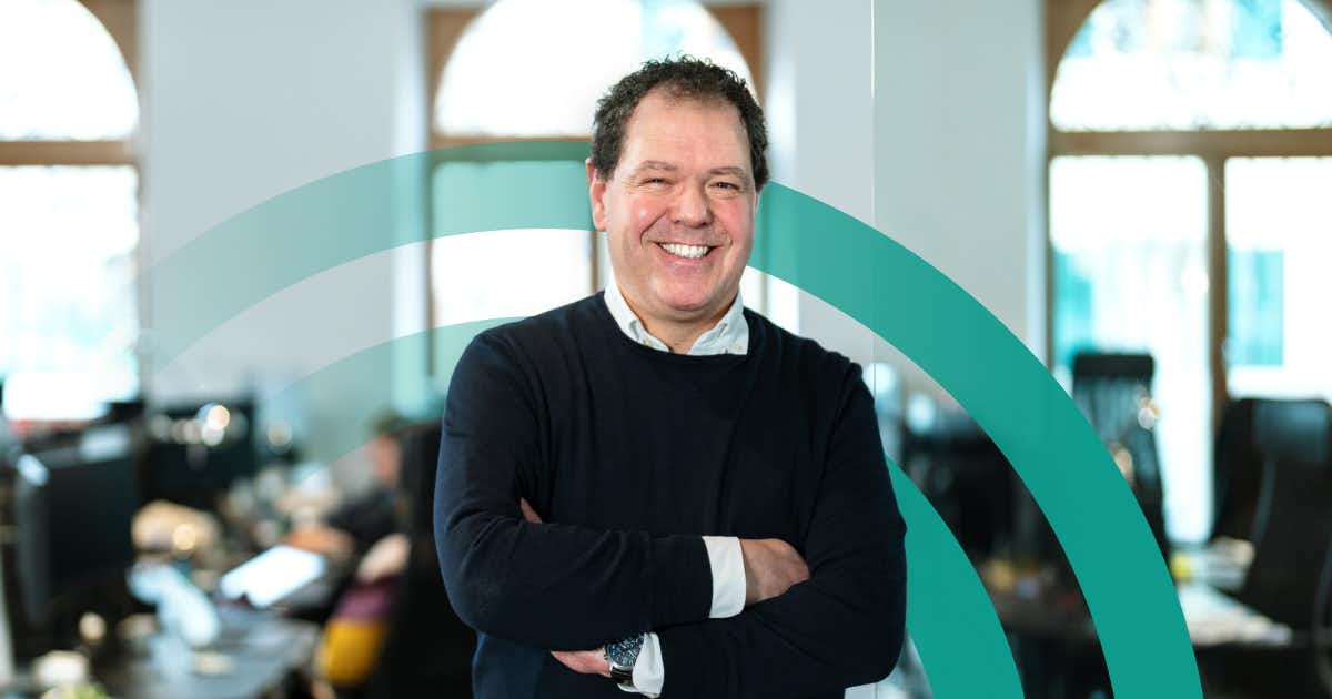 Man in an office setting smiling with arms crossed.