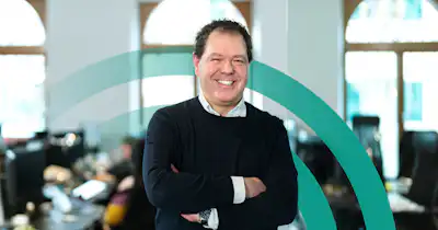 Man in an office setting smiling with arms crossed.