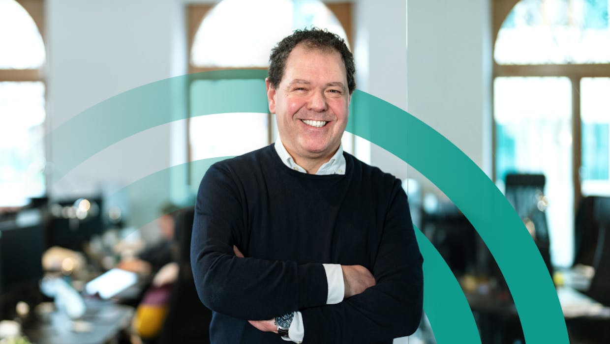 Man in an office setting smiling with arms crossed.