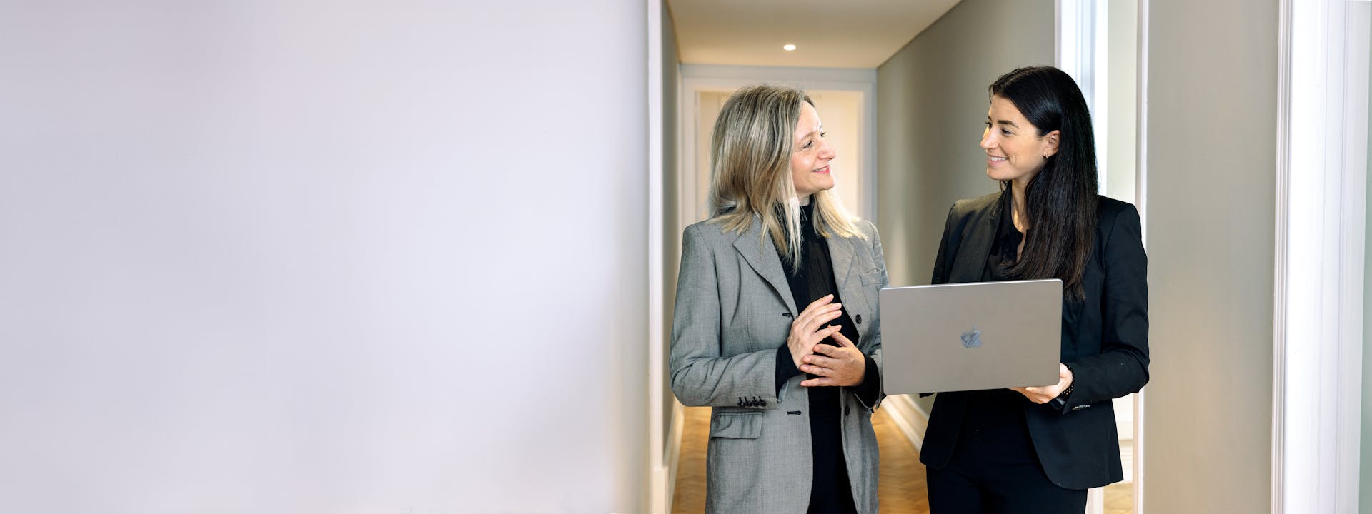 Two ladies talking in a office setting hallway
