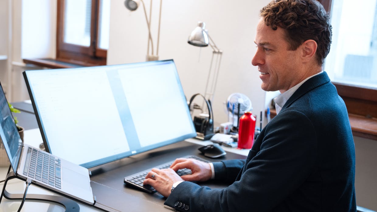 Man in an office setting typing on a computer.