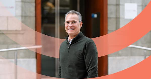 A man smiling and a circle graphic device in the background.