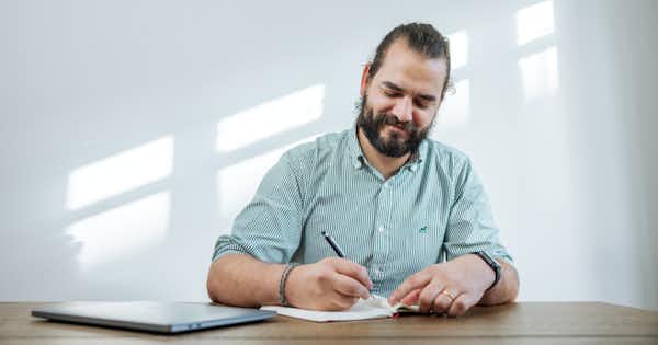 a picture of a man smiling writing on paper