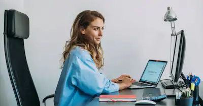 A woman working on her laptop at a desk.