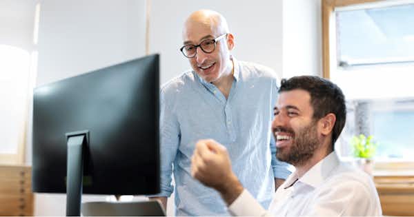 Deux hommes regardant l'écran d'un ordinateur de bureau.