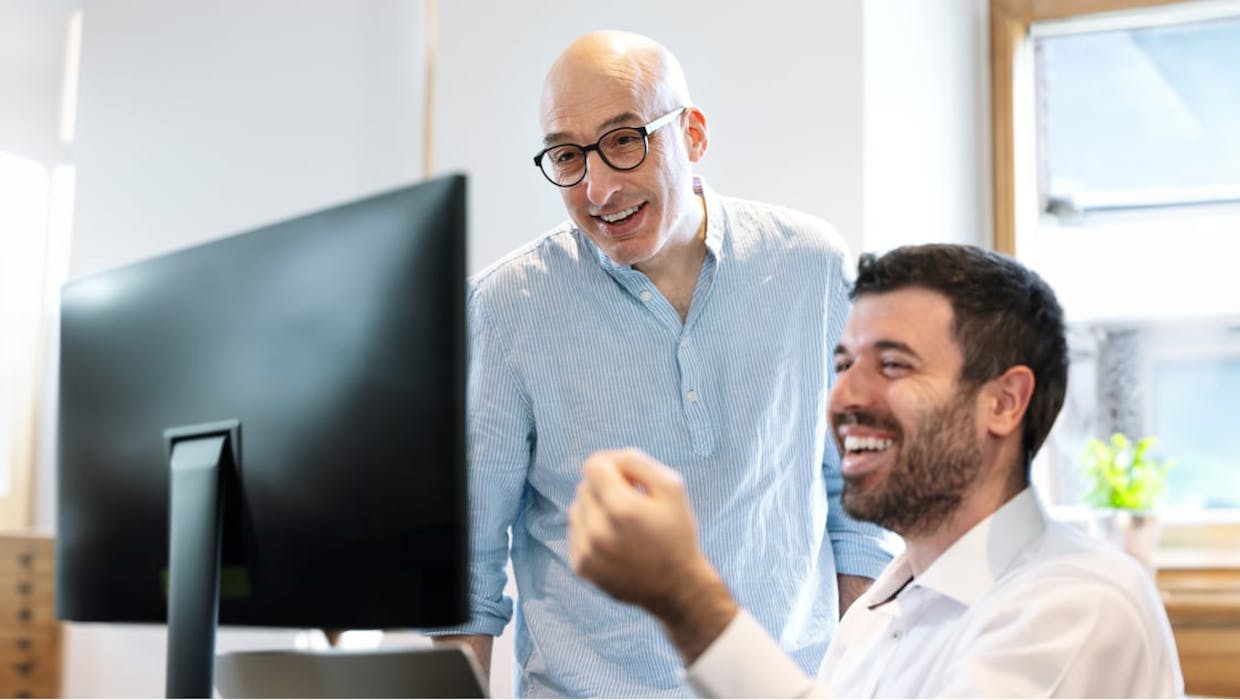 Deux hommes regardant l'écran d'un ordinateur de bureau.