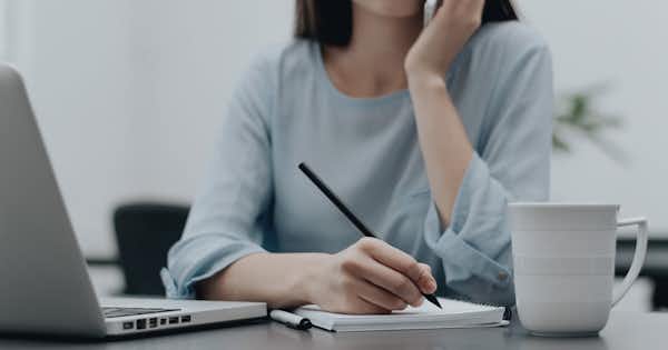 Woman with head resting on chin looking a computer