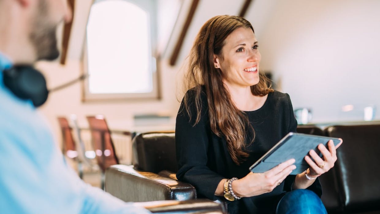 Femme souriante tenant un ordinateur portable.