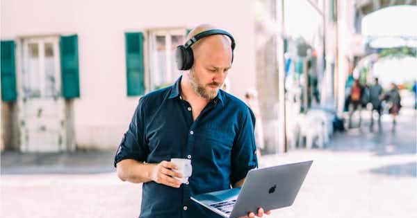 Man holding cup in one hand and laptop in the other