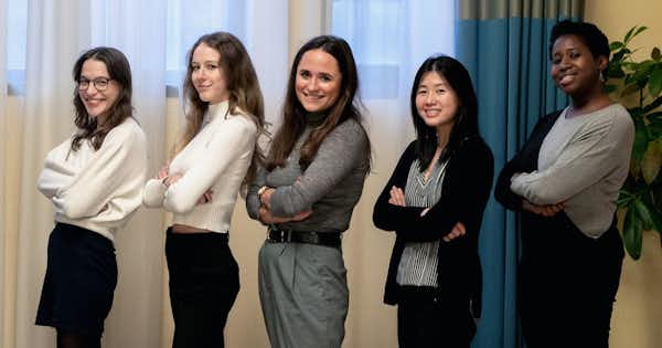 Five women standing with arms folded