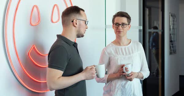 Man and woman standing with coffee cups and talking