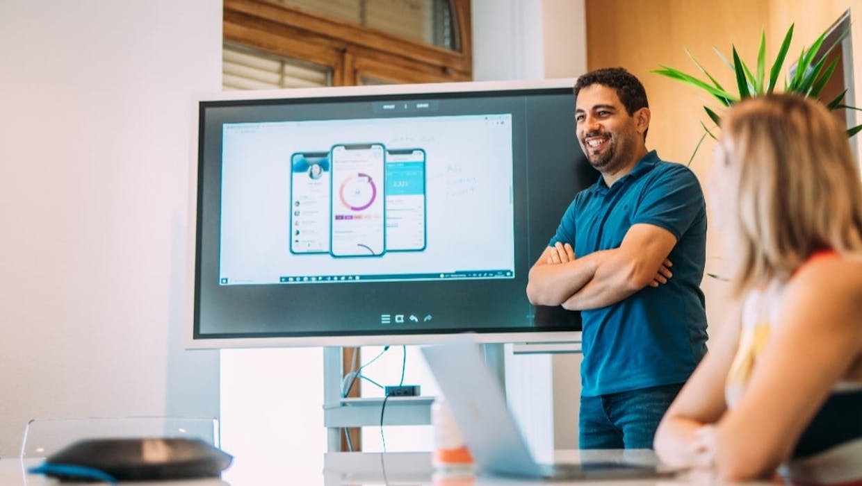 Un homme devant une salle présentant des données sur un grand écran.