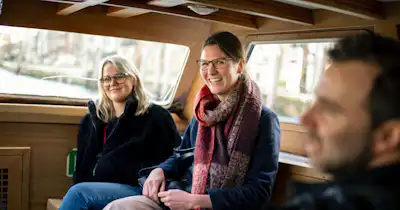 Two women and one man inside a vehicle, laughing