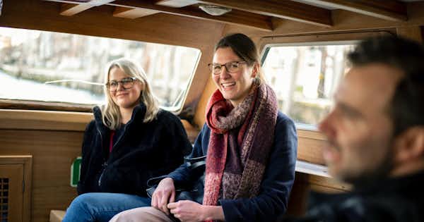 Two women and one man inside a vehicle, laughing