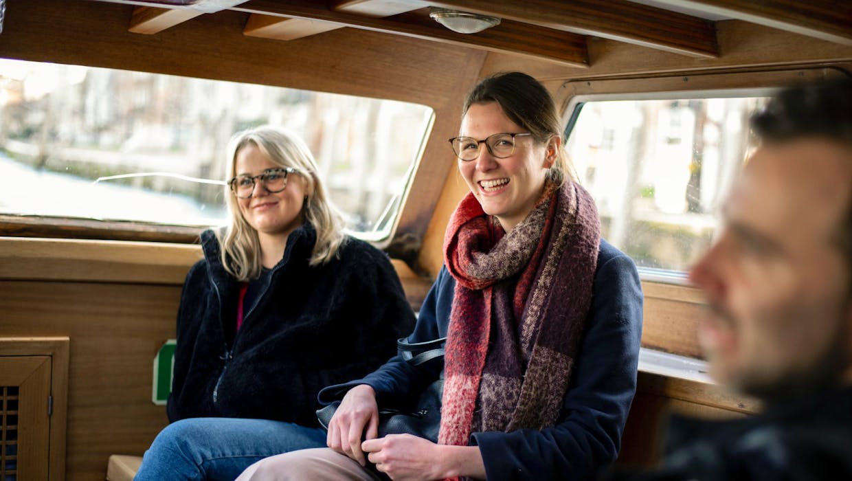 Deux femmes et un homme à l'intérieur d'un véhicule, en train de rire.