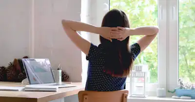 Femme penchée en arrière sur une chaise, les mains derrière la tête.
