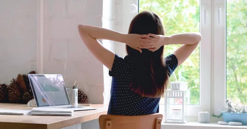 Woman leaning back in chair with hands folded behind her head