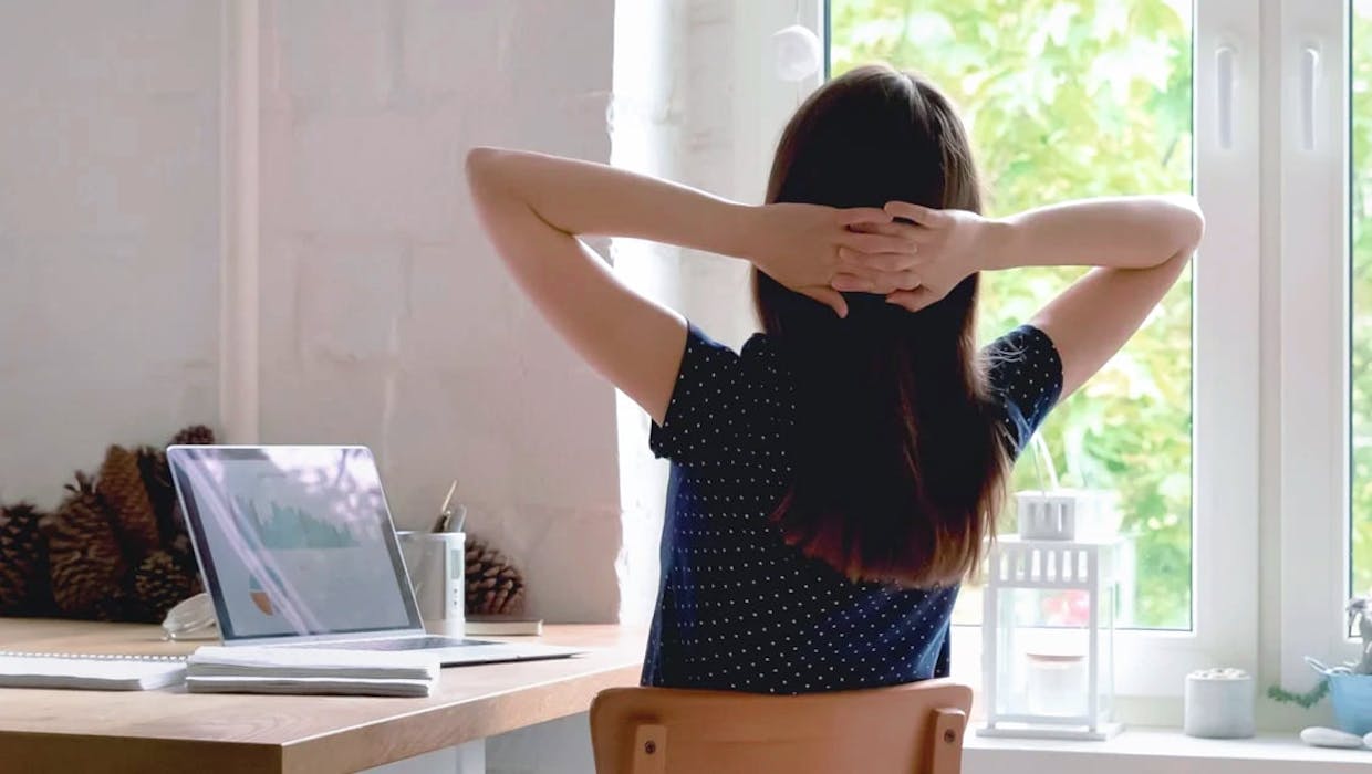 Femme penchée en arrière sur une chaise, les mains derrière la tête.