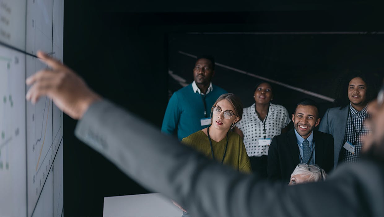 Homme montrant des chiffres sur un tableau devant un groupe